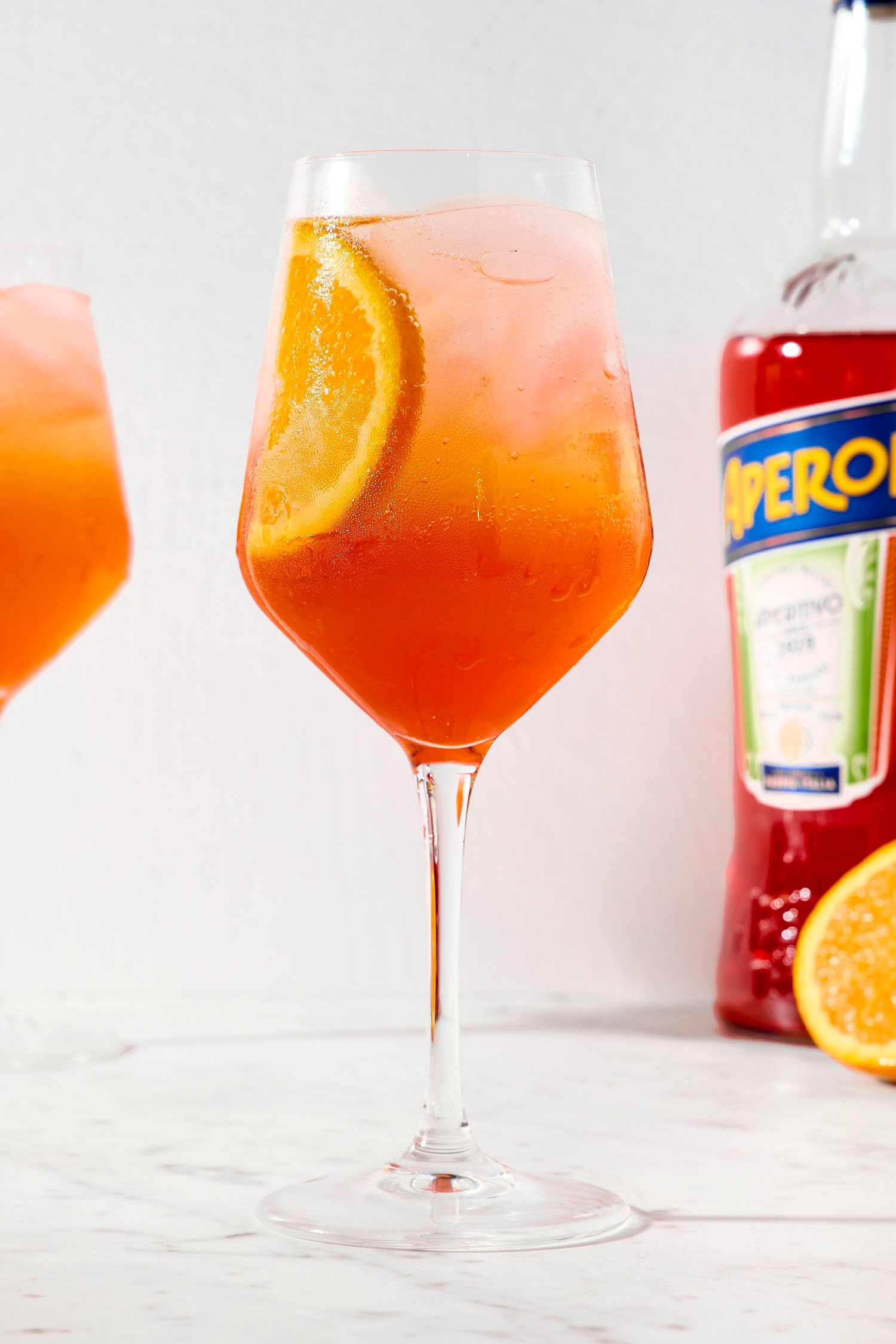 Wine glass filled with Aperol spritz cocktail with orange color.