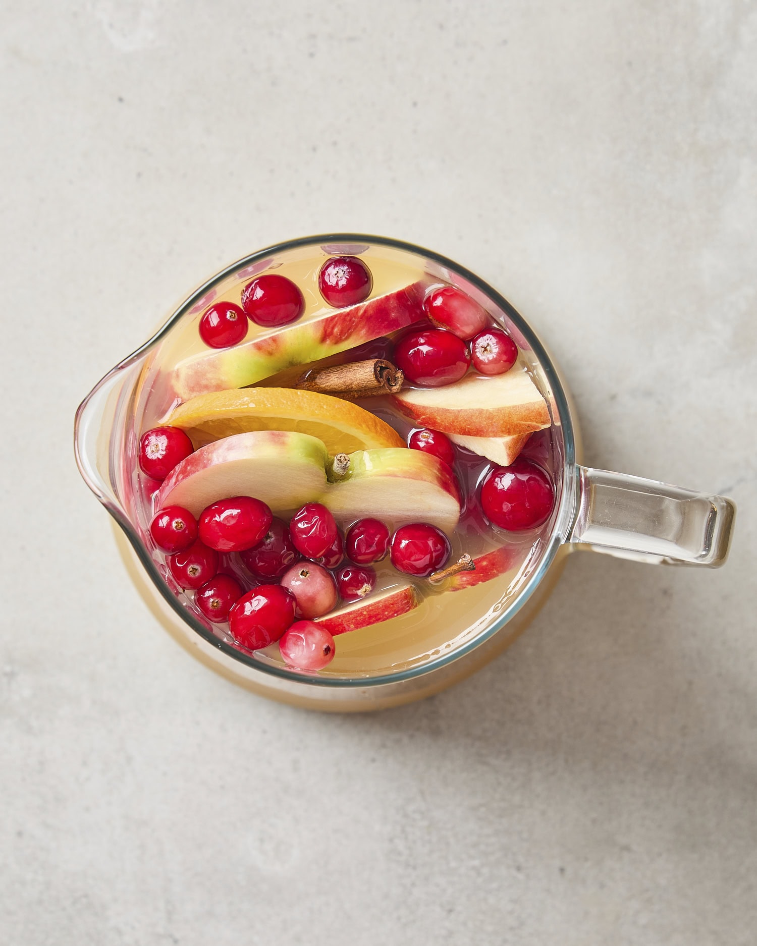 Glass pitcher filled with mixed together apple cider sangria.