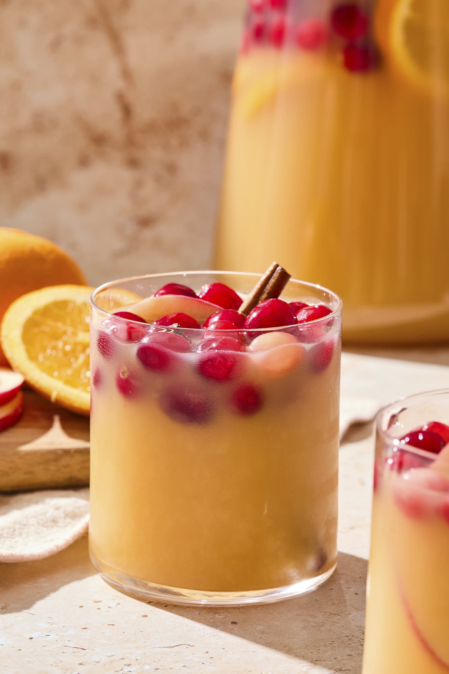 Glass of sangria with fall garnishes with pitcher filled with more in the background.