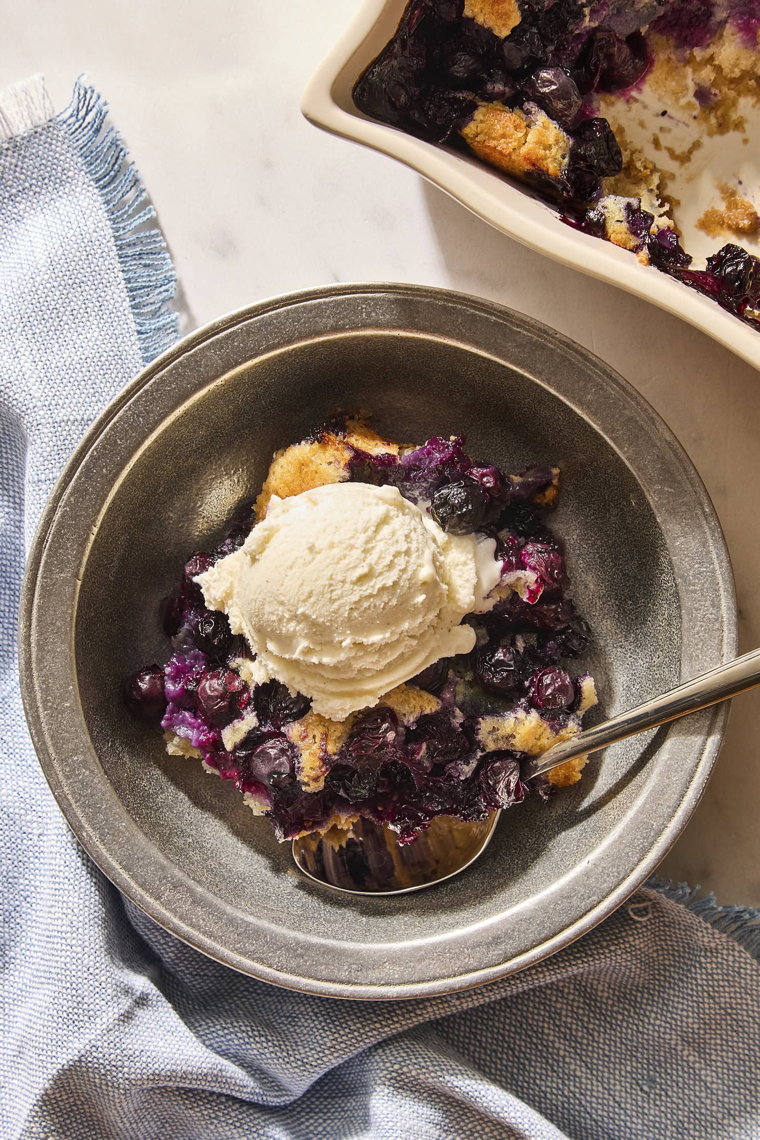 Serving of blueberry cobbler with scoop of ice cream on top.