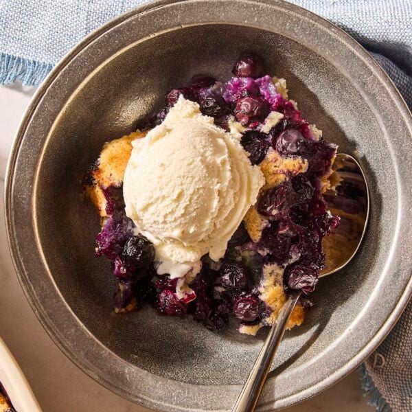 Serving of cobbler in a bowl with scoop of ice cream on top.