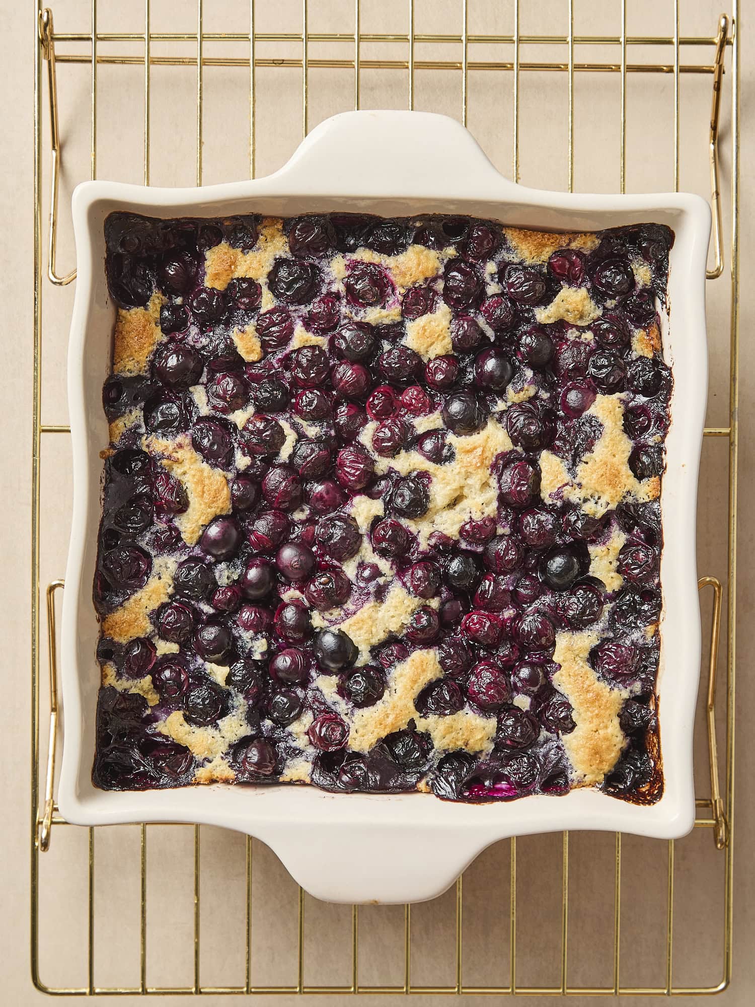 White baking dish with blueberry cobbler on cooling rack.