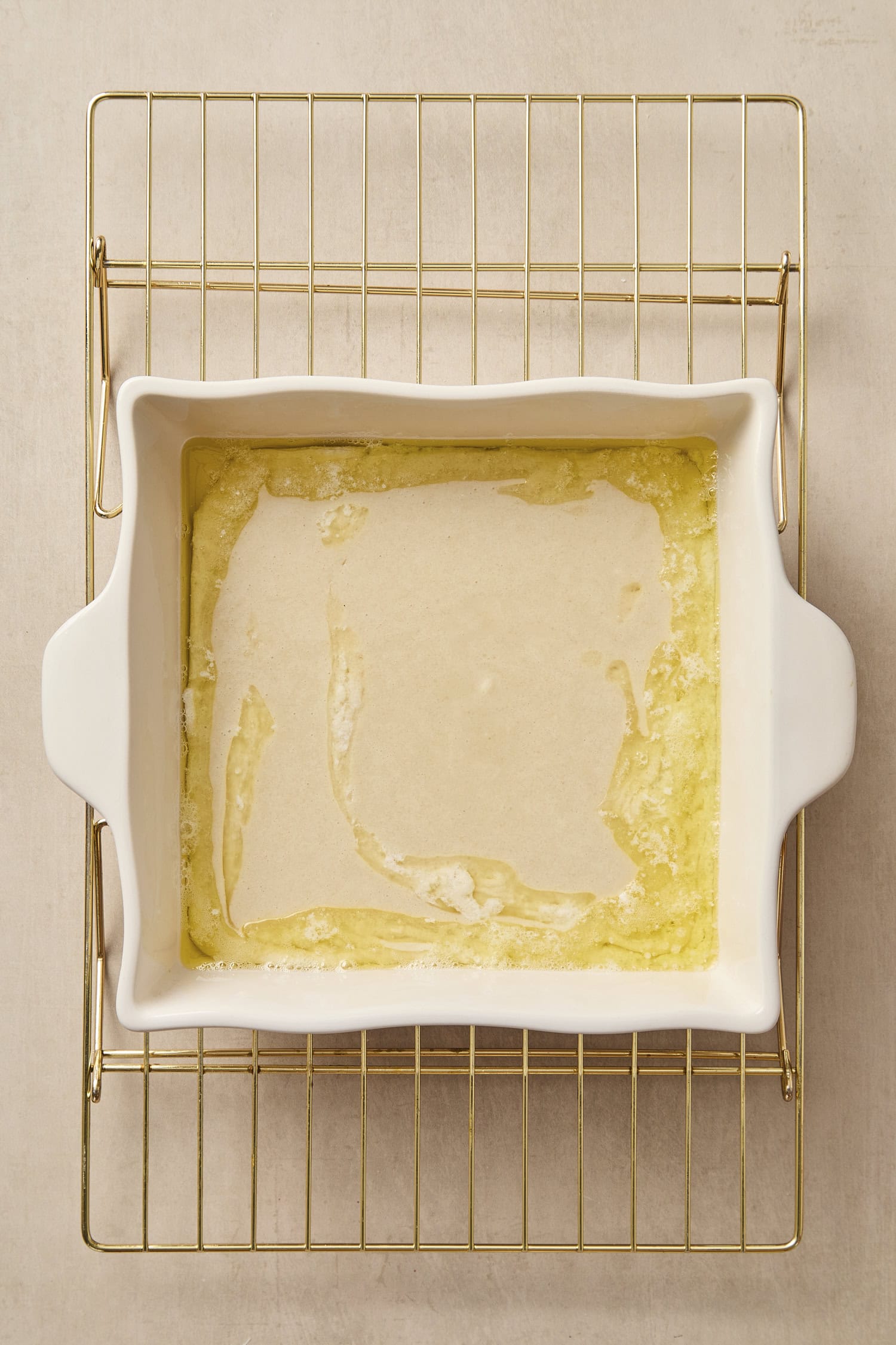 White baking dish with melted butter and batter.