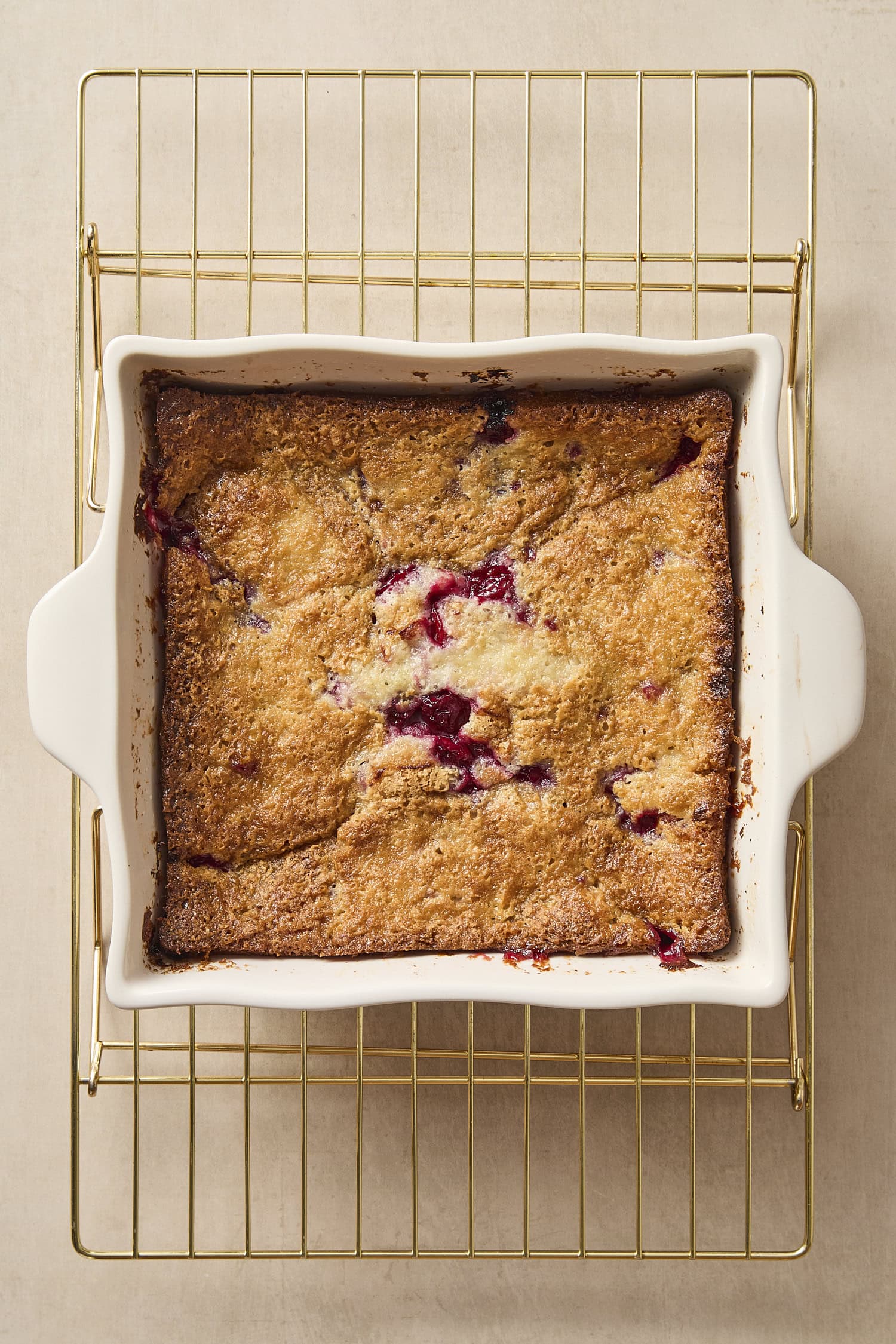 Baked cherry cobbler in baking pan with bits of cherry showing.