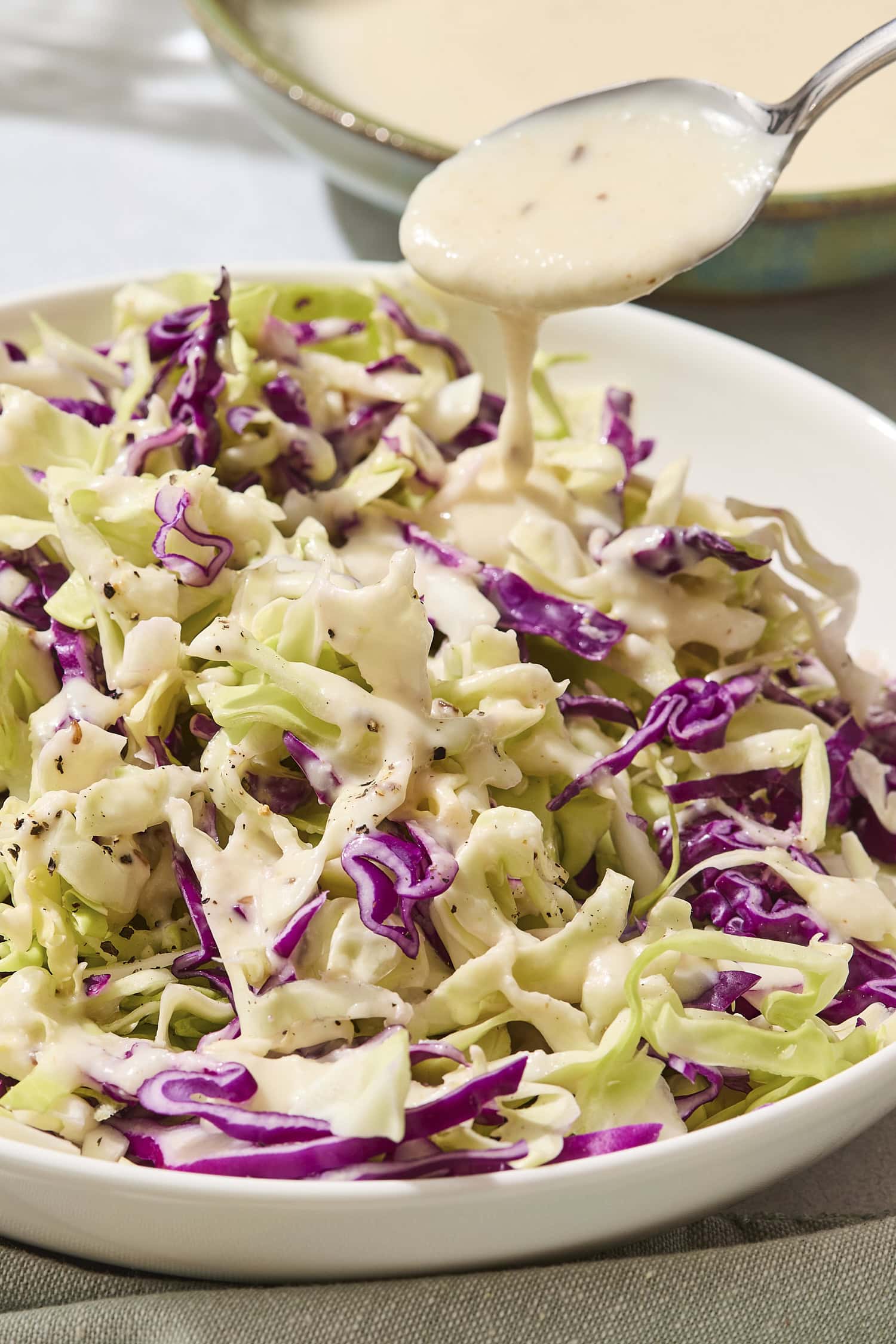 Cabbage with a creamy coleslaw dressing being poured over the top.