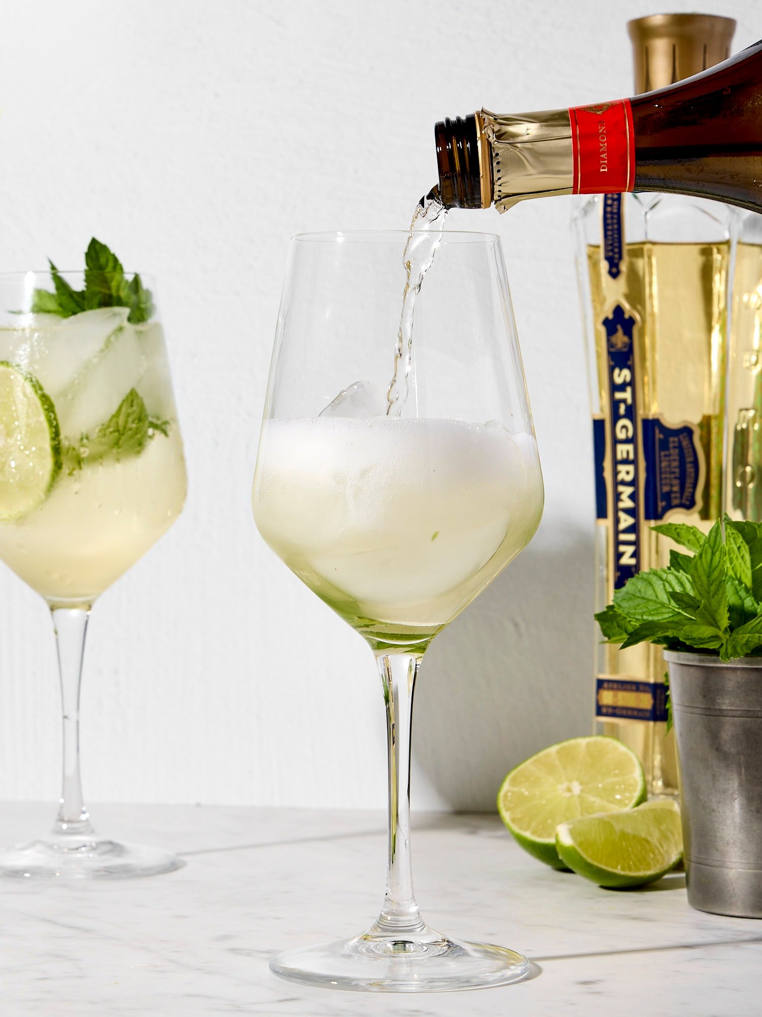 Wine glass with sparkling wine pouring in from bottle.