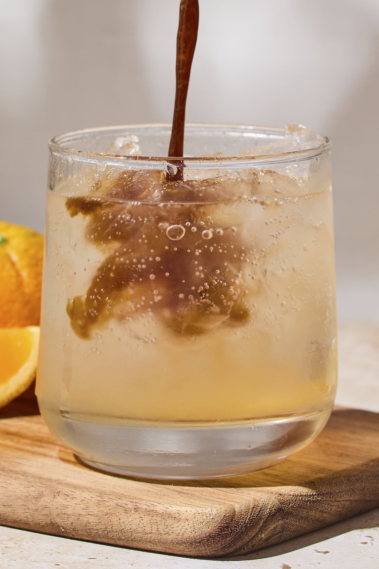 Shot of espresso pouring into a glass filled with tonic water and ice.