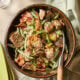 A bowl full of green bean and potato salad in a bowl on a tiled table.
