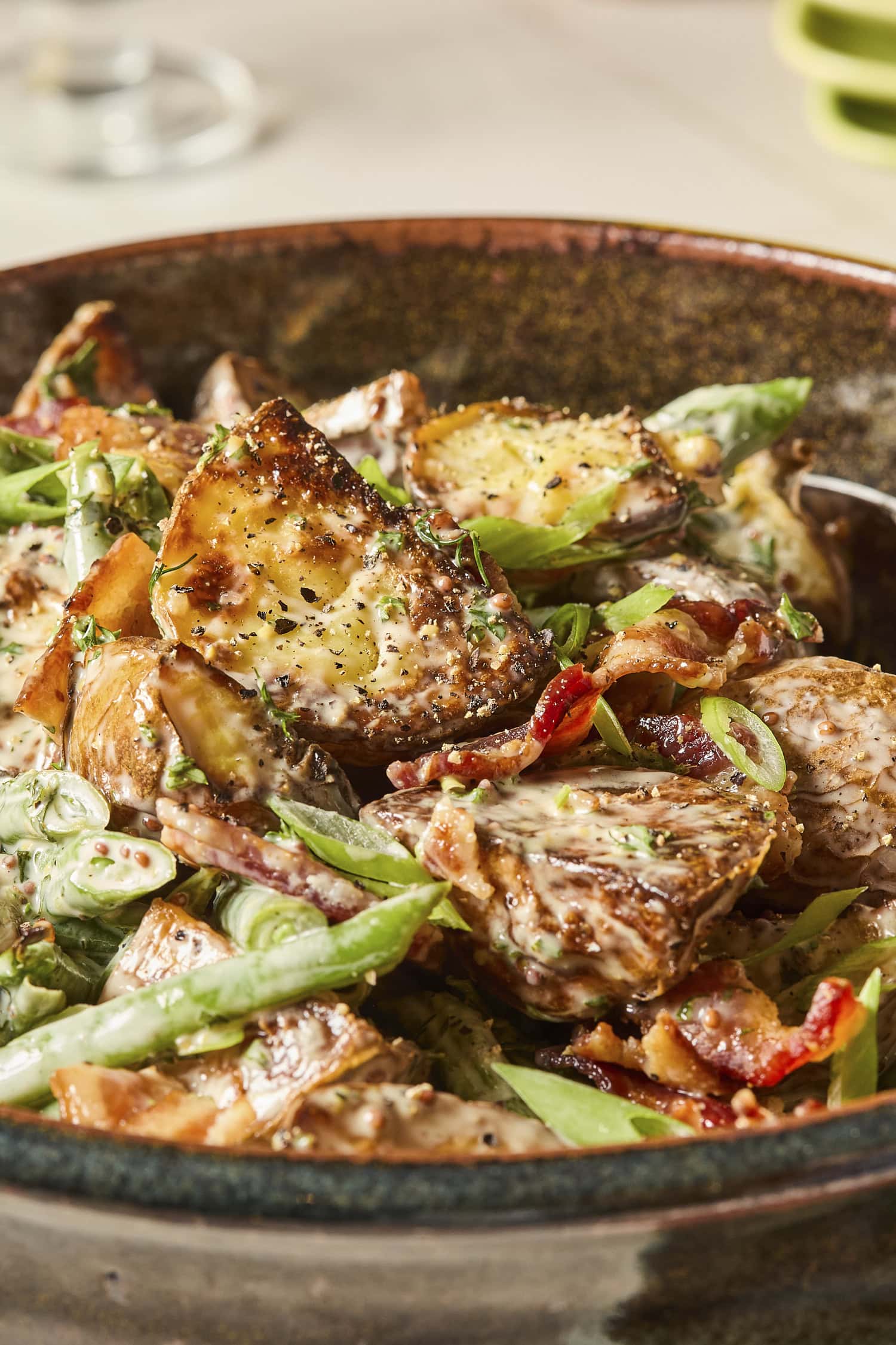Roasted green beans and potatoes covered in dressing in a bowl.