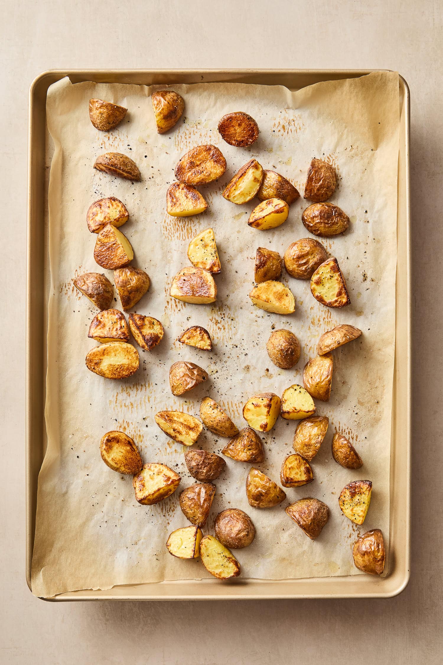 Roasted potato wedges on a parchment-lined baking sheet.