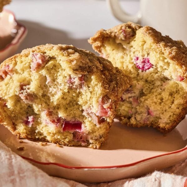 Rhubarb muffin split in half showing red pieces of rhubarb inside.