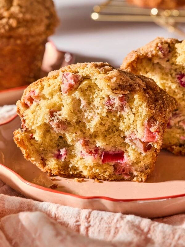 Rhubarb muffin split in half sitting on a plate with morning sunlight.