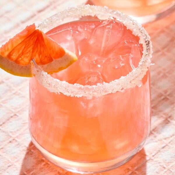 Light pink siesta cocktail with a grapefruit wedge in a glass.