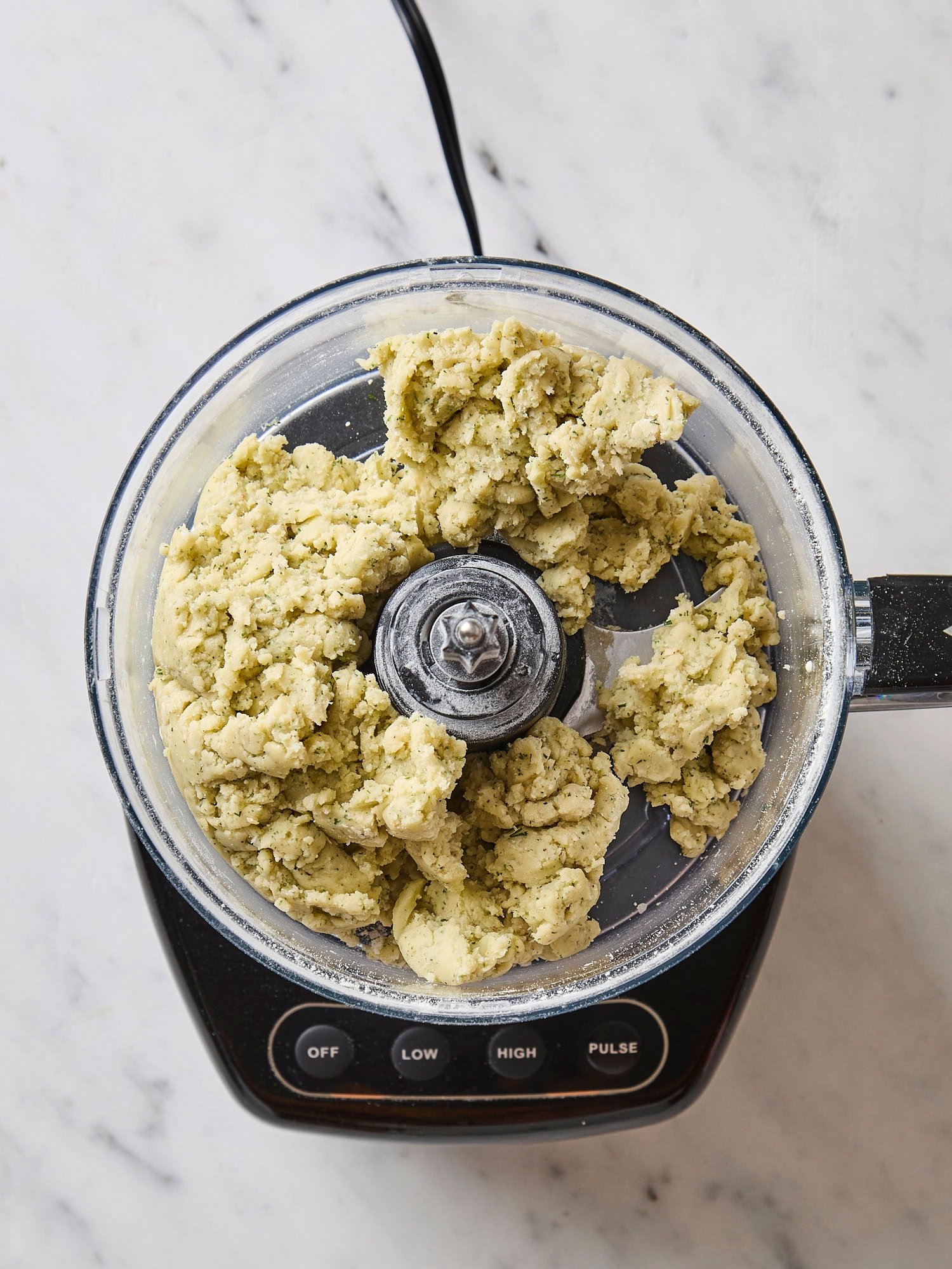 Food processor with crumbly dough mixture.