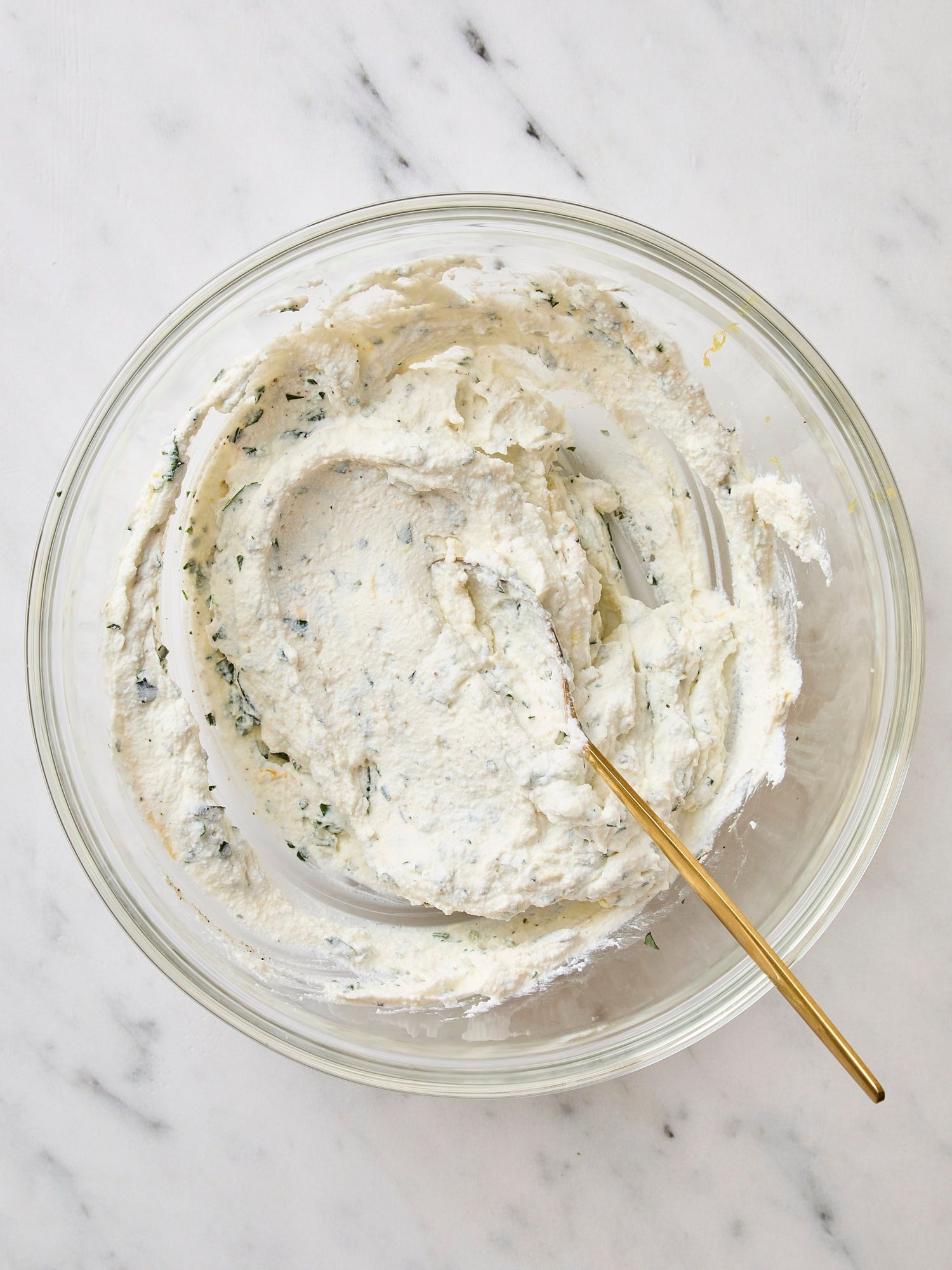 Glass bowl filled with ricotta mixture for the filling of a tomato tart.