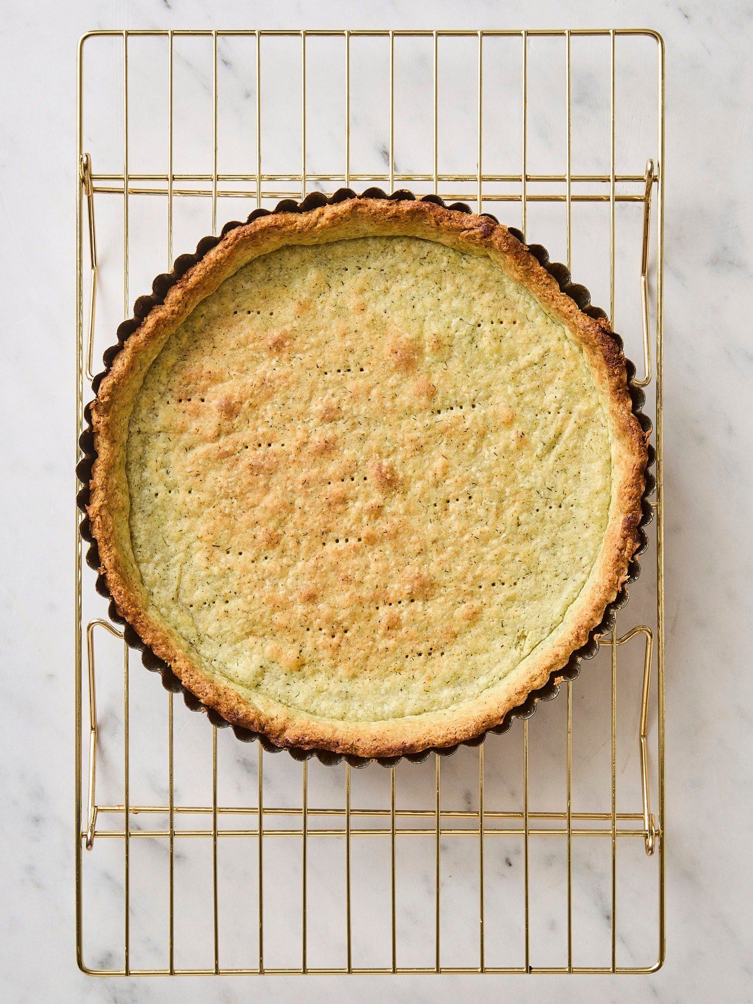 Baked crust with some herbs with golden color on cooling rack.