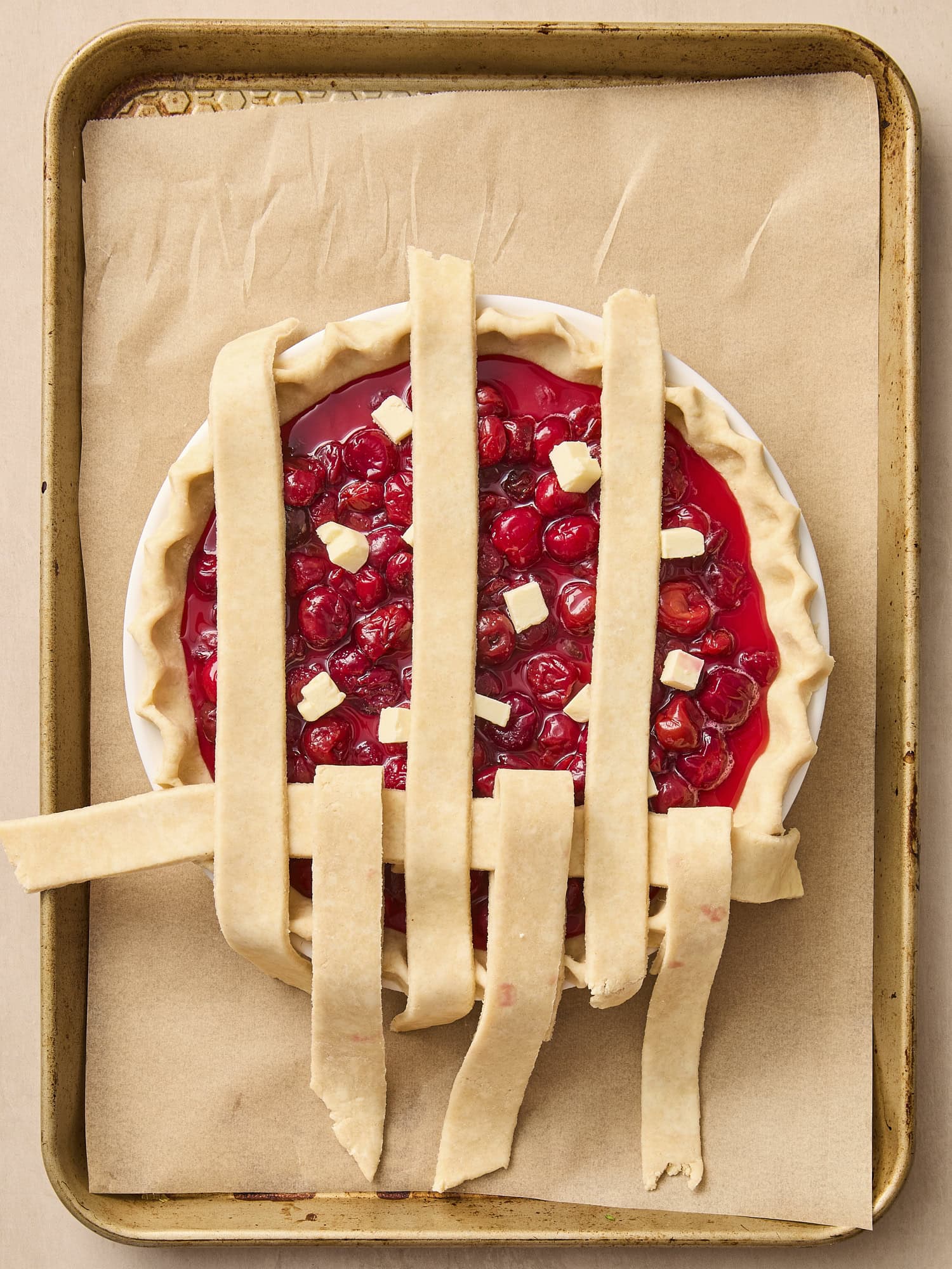 Cherry pie with lattice crust being assembled on top.