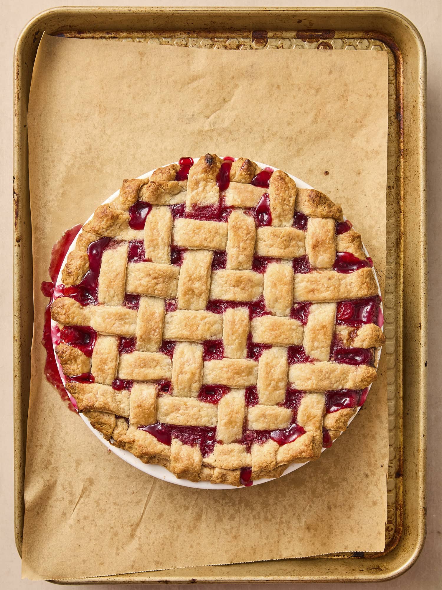 Baking sheet with fully cooked and baked cherry pie with lattice crust.