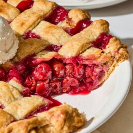 Sliced cherry pie showing filling with a lattice crust.