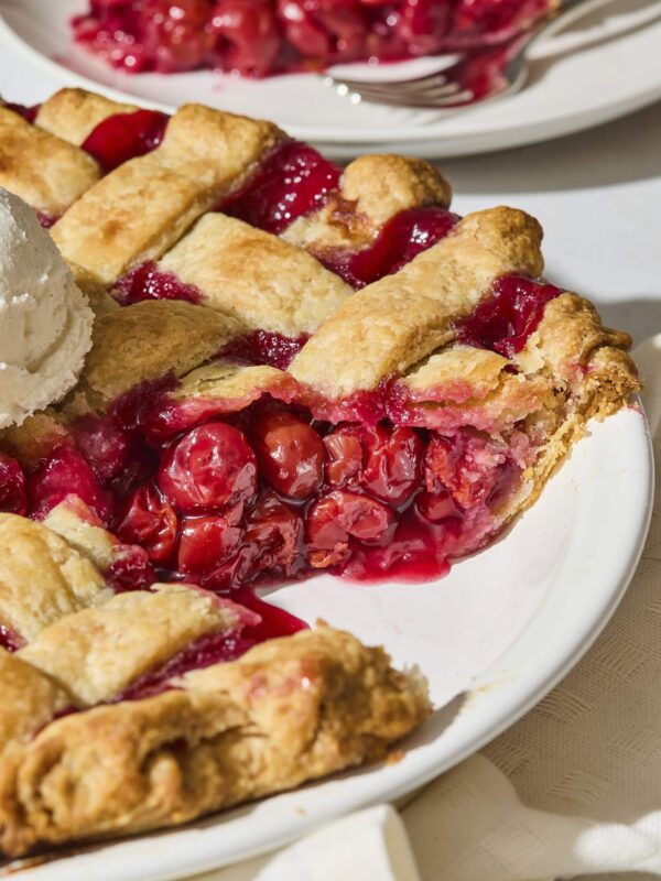 Sliced cherry pie showing filling with a lattice crust.