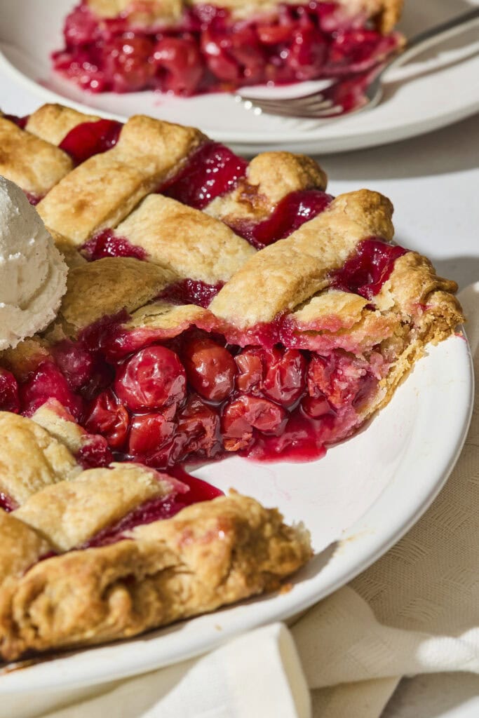 Sliced cherry pie showing filling with a lattice crust.
