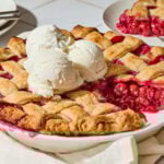 Cherry pie with scoops of ice cream on top and slice removed.
