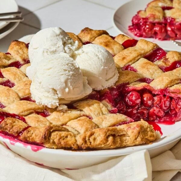 Cherry pie with scoops of ice cream on top and slice removed.
