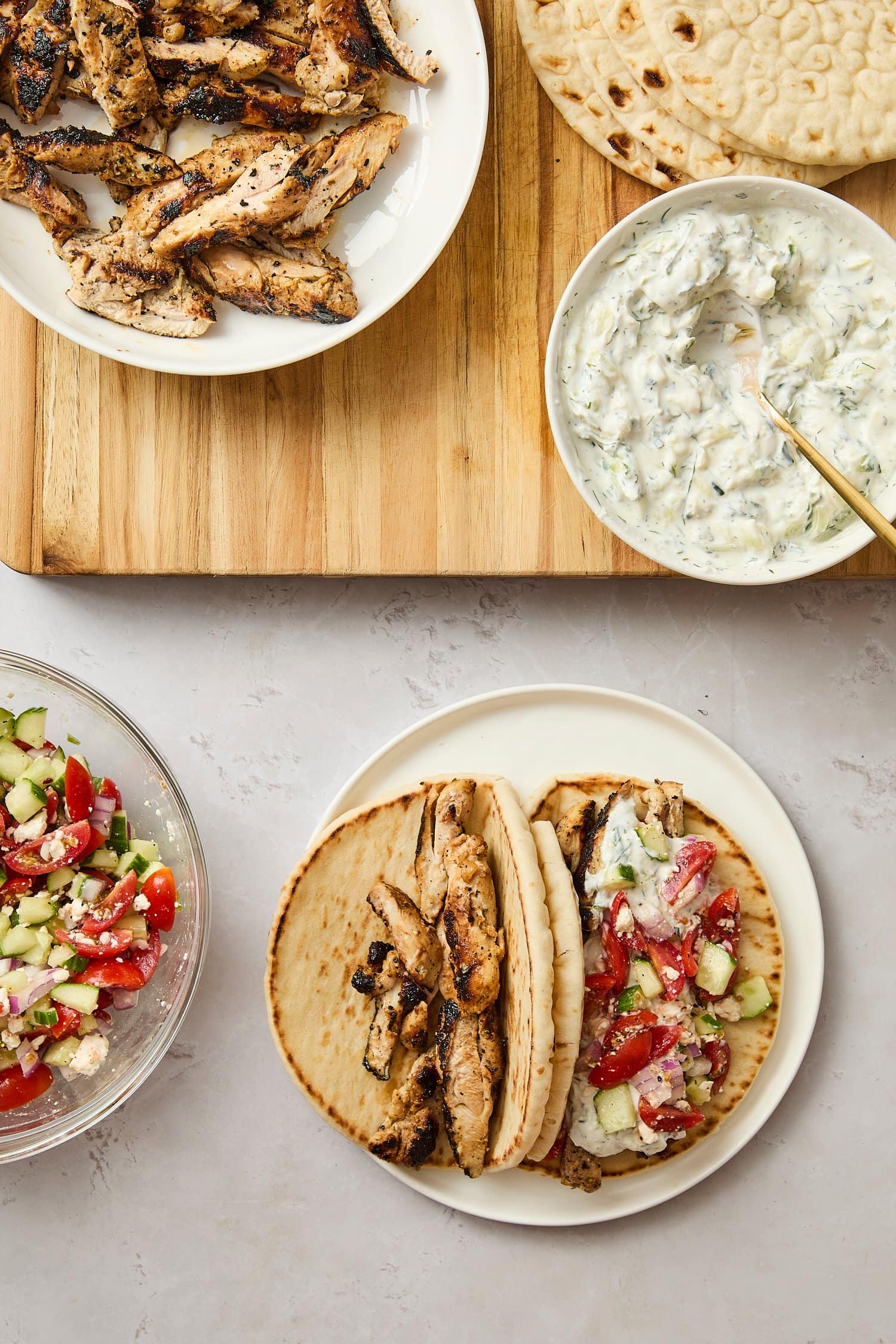 Plate with assembly of chicken gyros with tzatziki sauce.