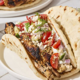 Pita with chicken gyros topped with Greek salad, feta, and tzatziki sauce.