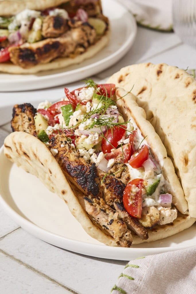 Pita with chicken gyros topped with Greek salad, feta, and tzatziki sauce.