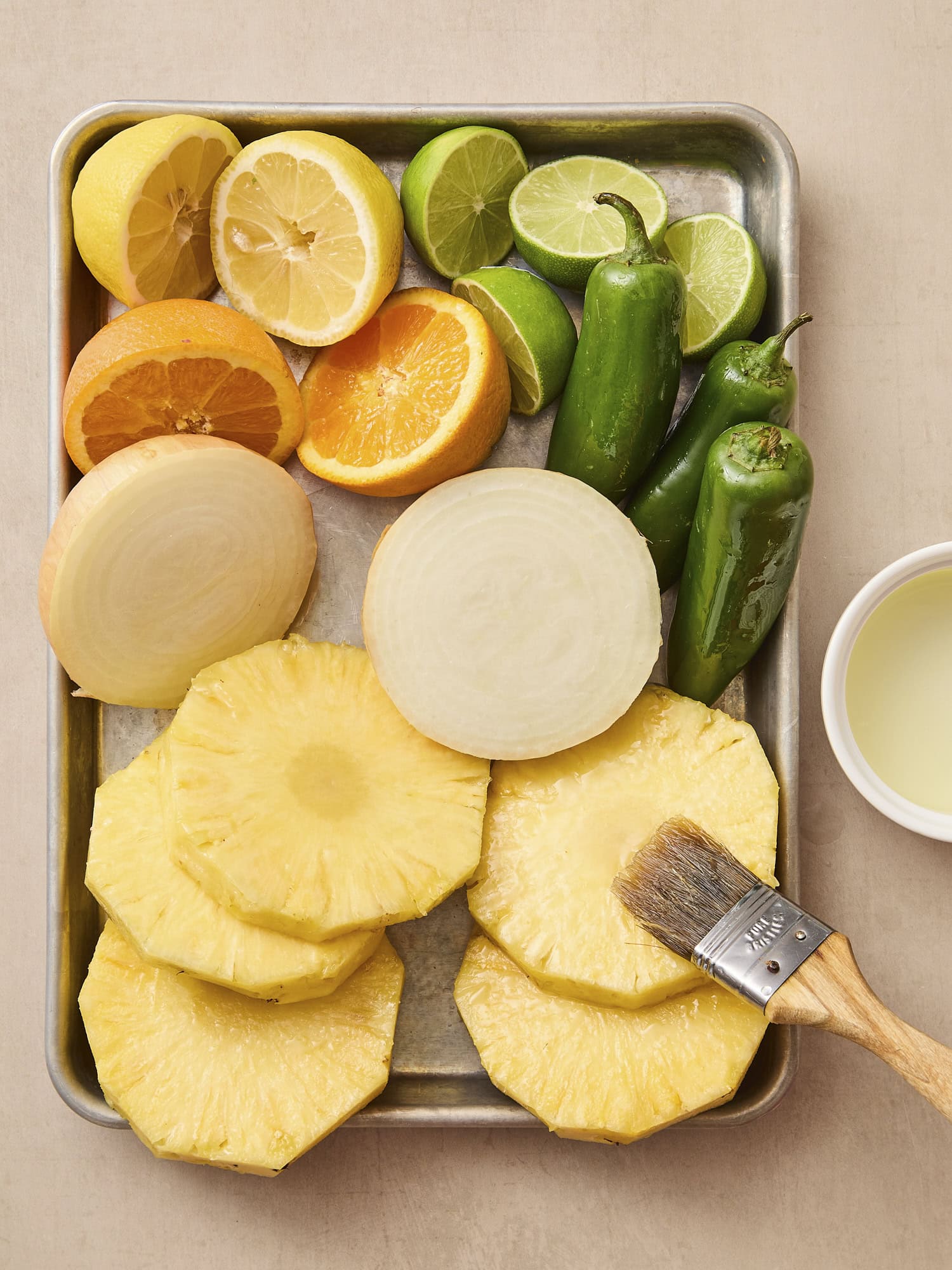 Sliced pieces of pineapple, citrus, onion, and jalapeno brushed with oil.