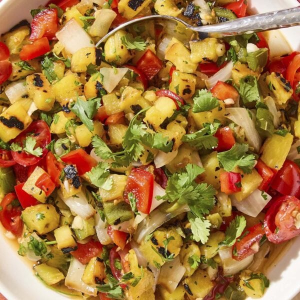 White bowl filled with pineapple salsa with spoon scooping out serving.