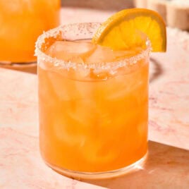 Orange colored Italian margarita in a glass with an orange slice.