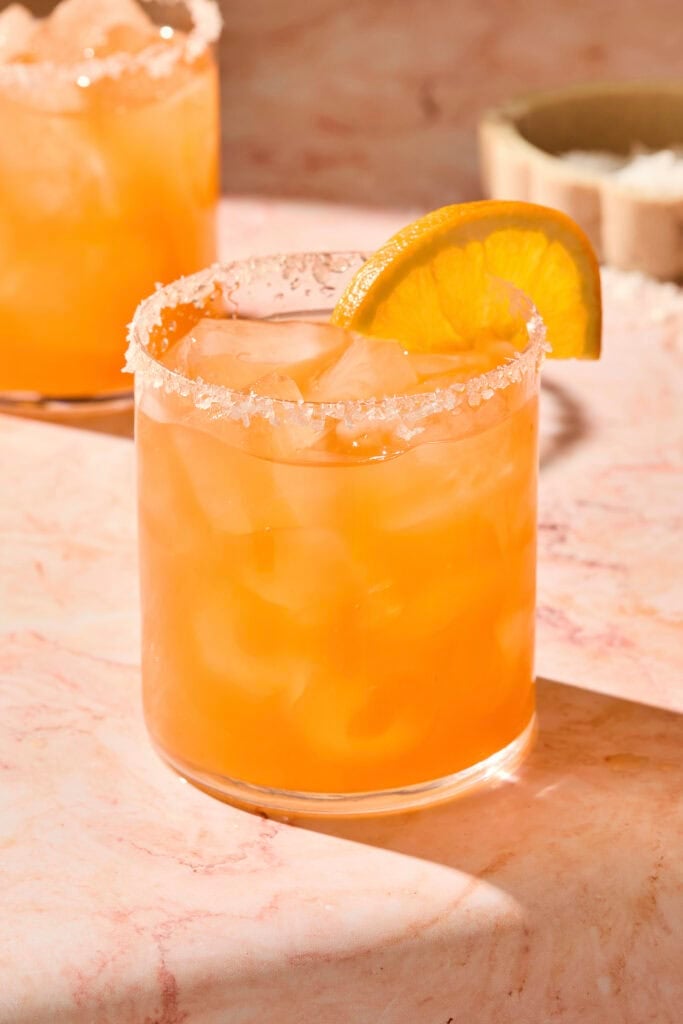 Orange colored Italian margarita in a glass with an orange slice.