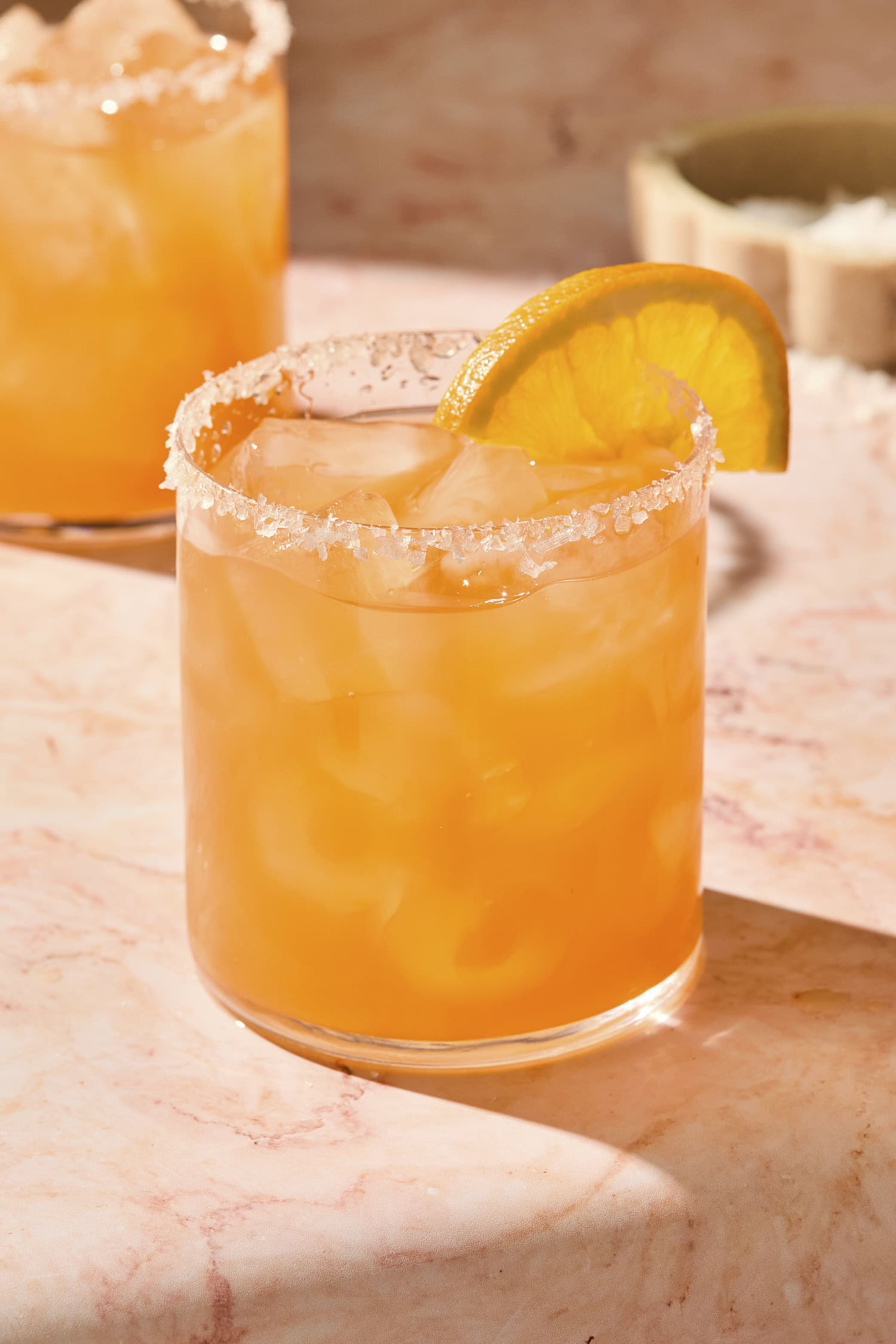 Orange colored Italian margarita in a glass with an orange slice.