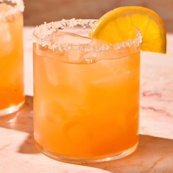 Glass filled with Italian margarita with a slice of orange on the rim.