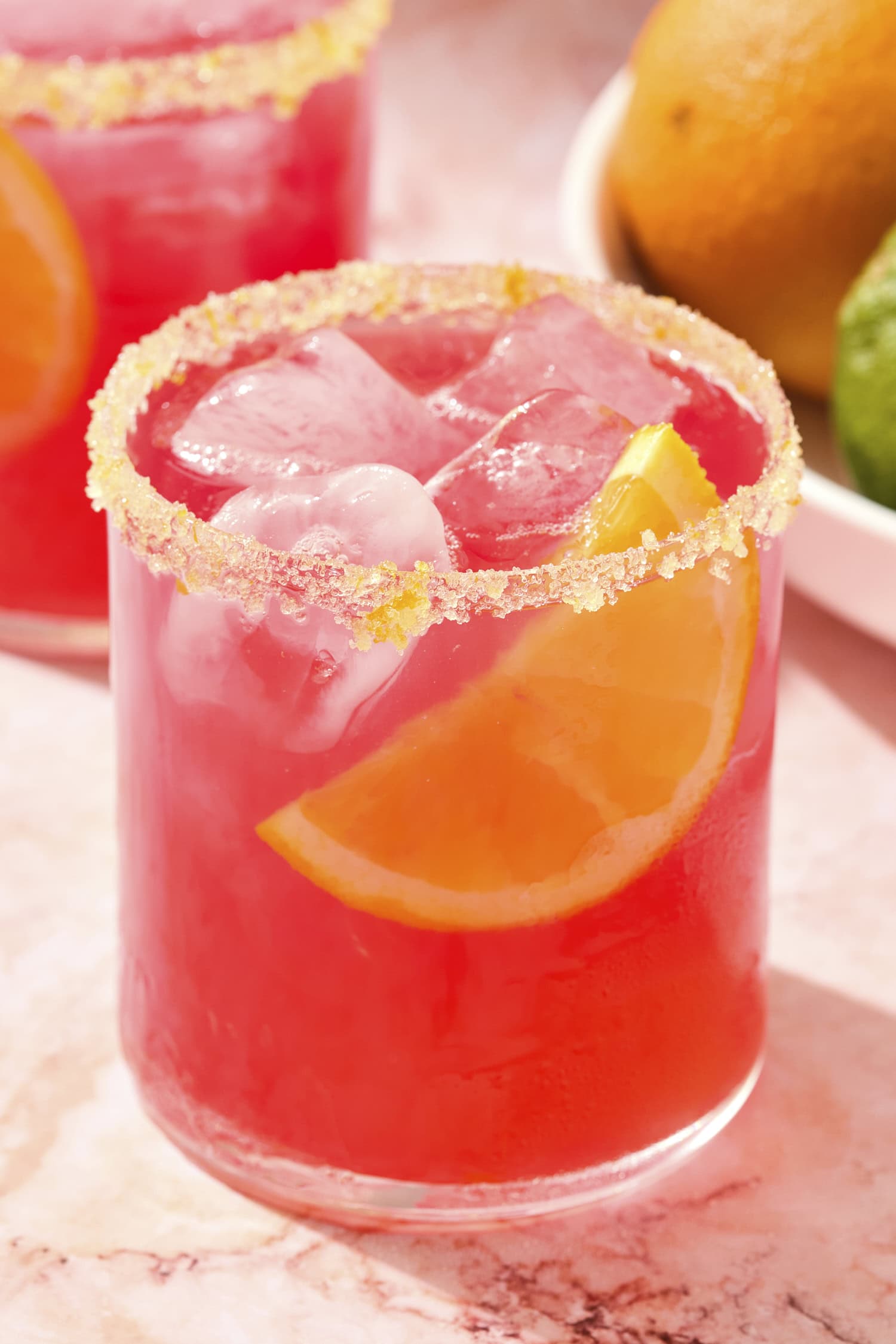 Rhubarb margarita with slice of orange with bright pink color.