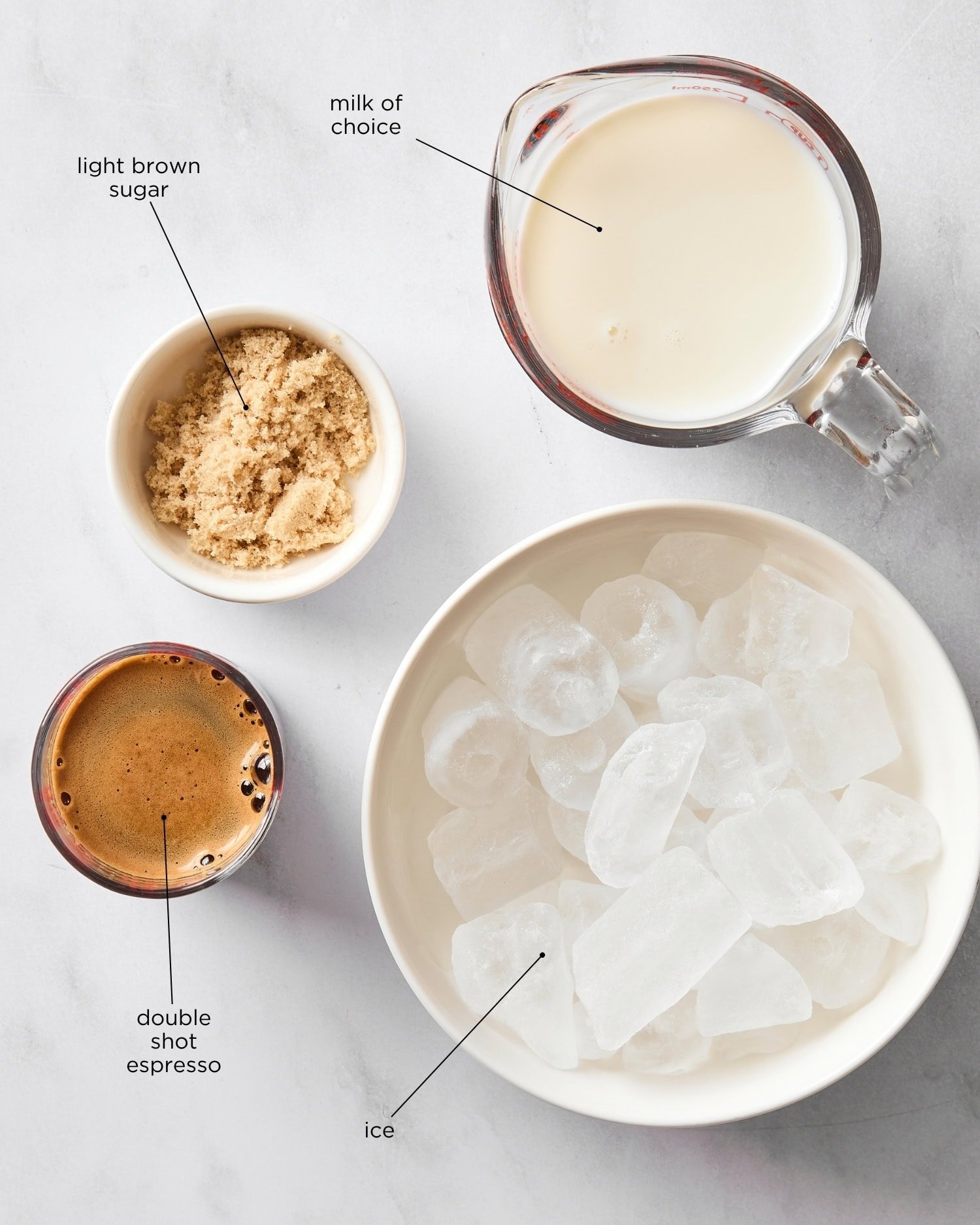 White marble surface with four ingredients for a shaken espresso.