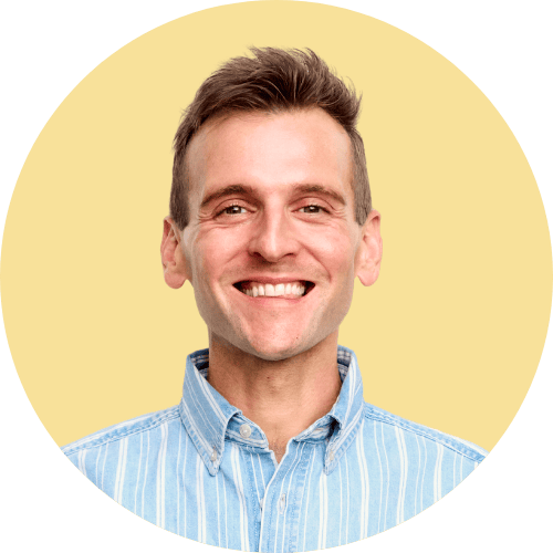 Kaleb Wyse standing in front of yellow background with a blue striped shirt.