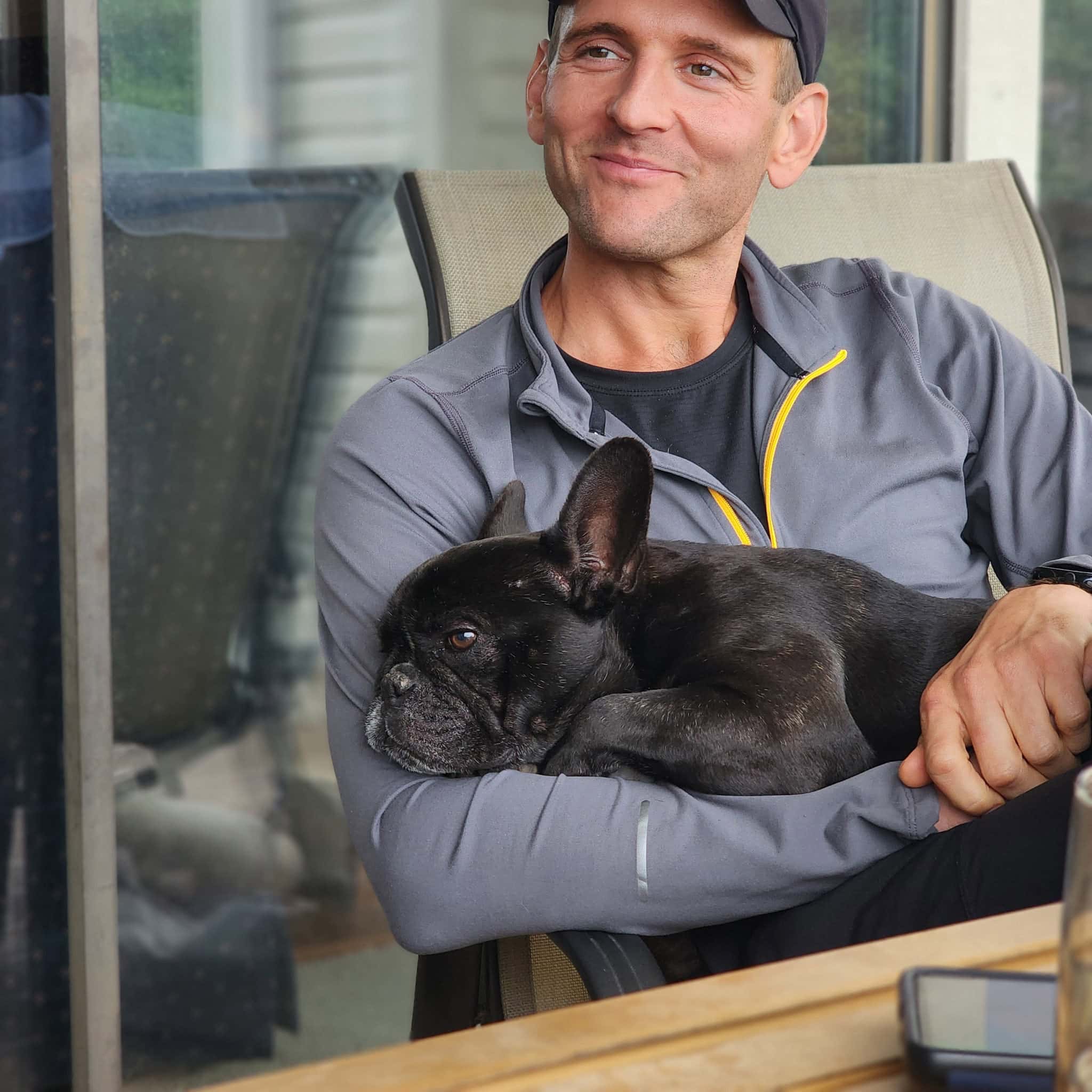 Kaleb Wyse holding his black French bulldog named Kip.