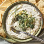 Green bowl filled with whipped feta dip topped with herbs and lemon zest.