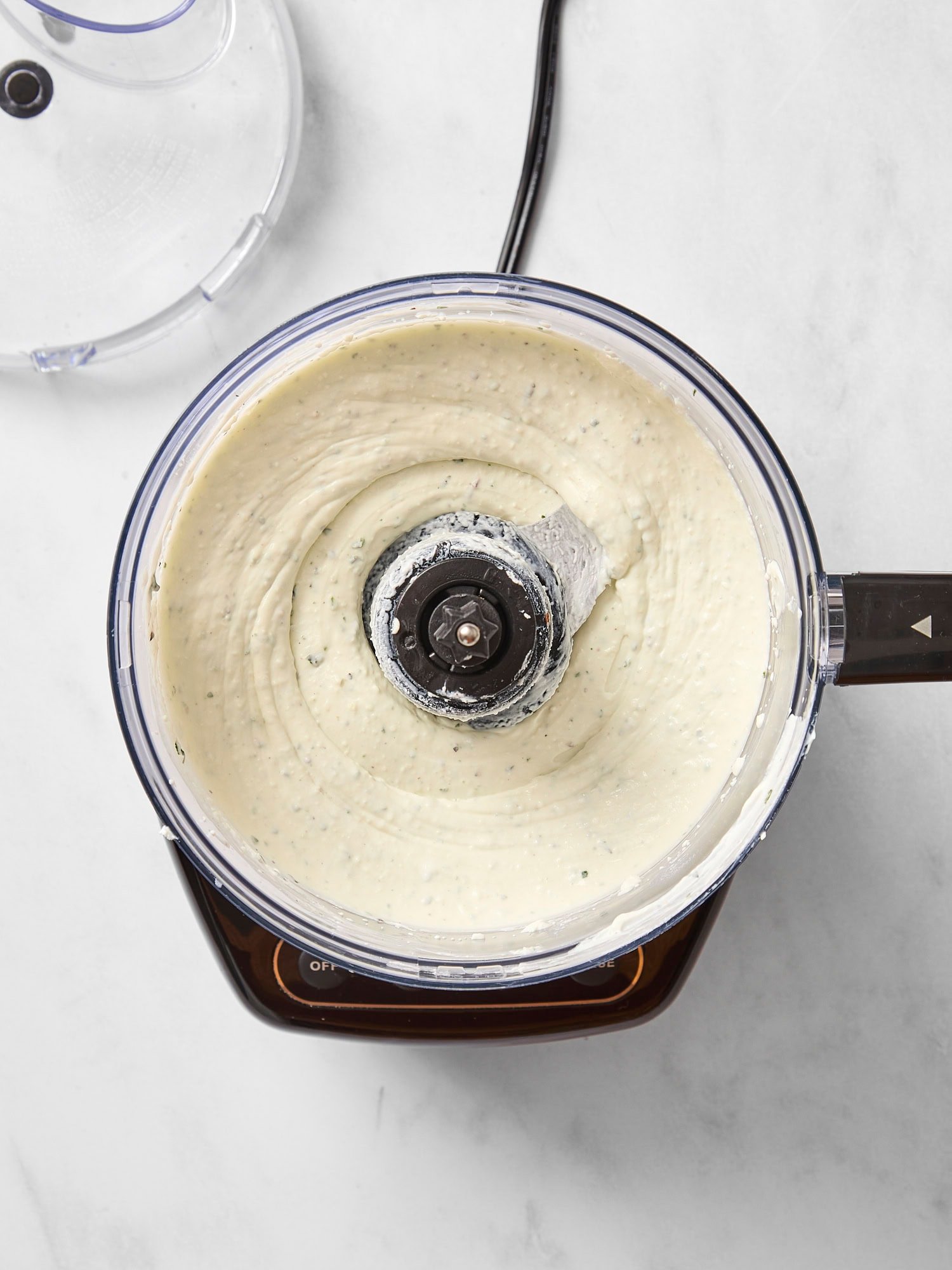 Food processor with whipped goat cheese after being processed.