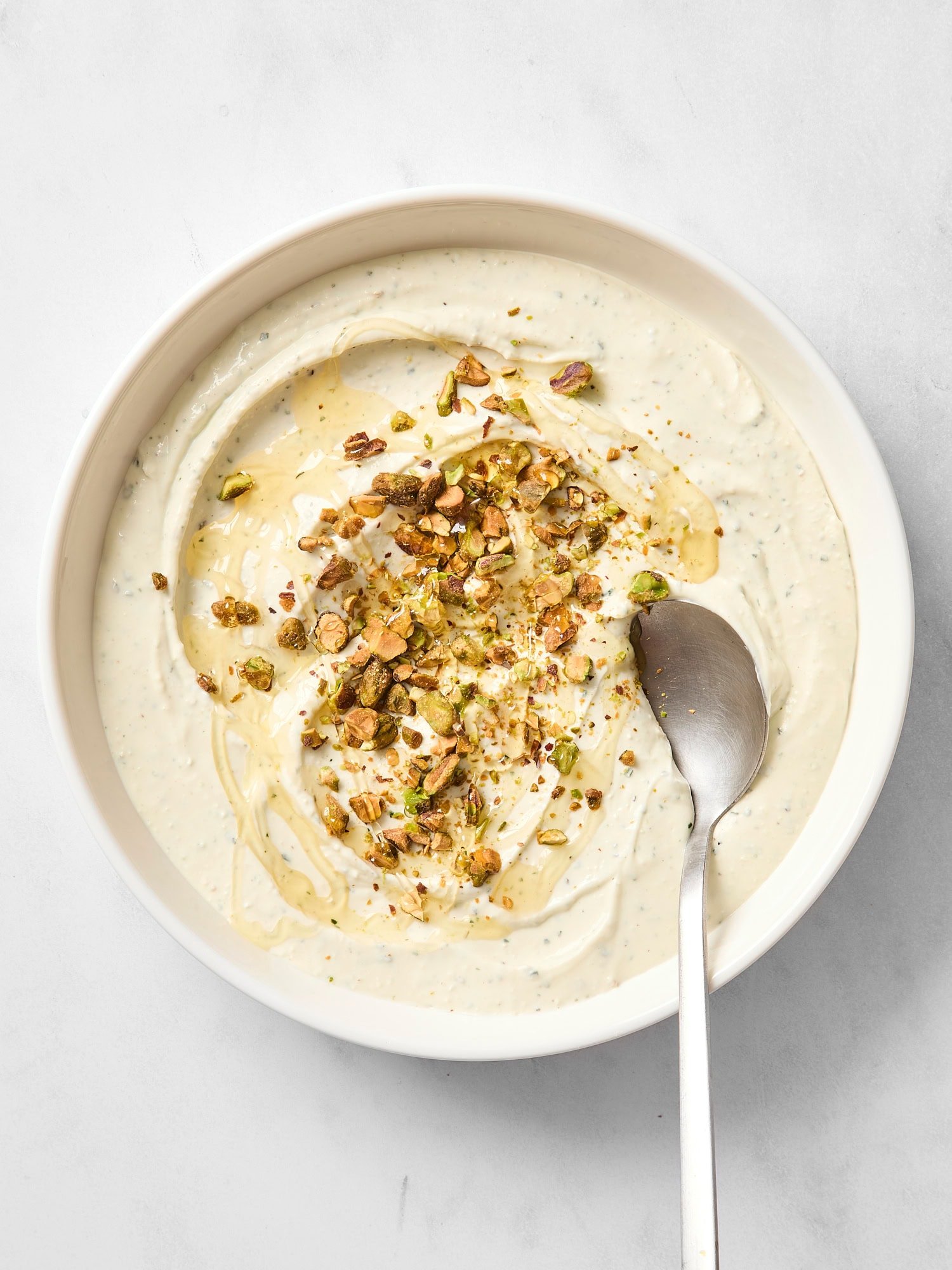 White bowl with whipped goat cheese dip with a spoon scooping out a serving.
