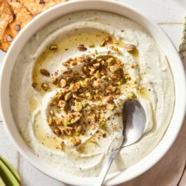 White bowl filled with whipped goat cheese topped with pistachios and hot honey.