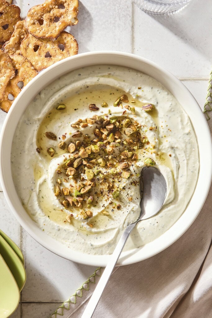White bowl filled with whipped goat cheese topped with pistachios and hot honey.