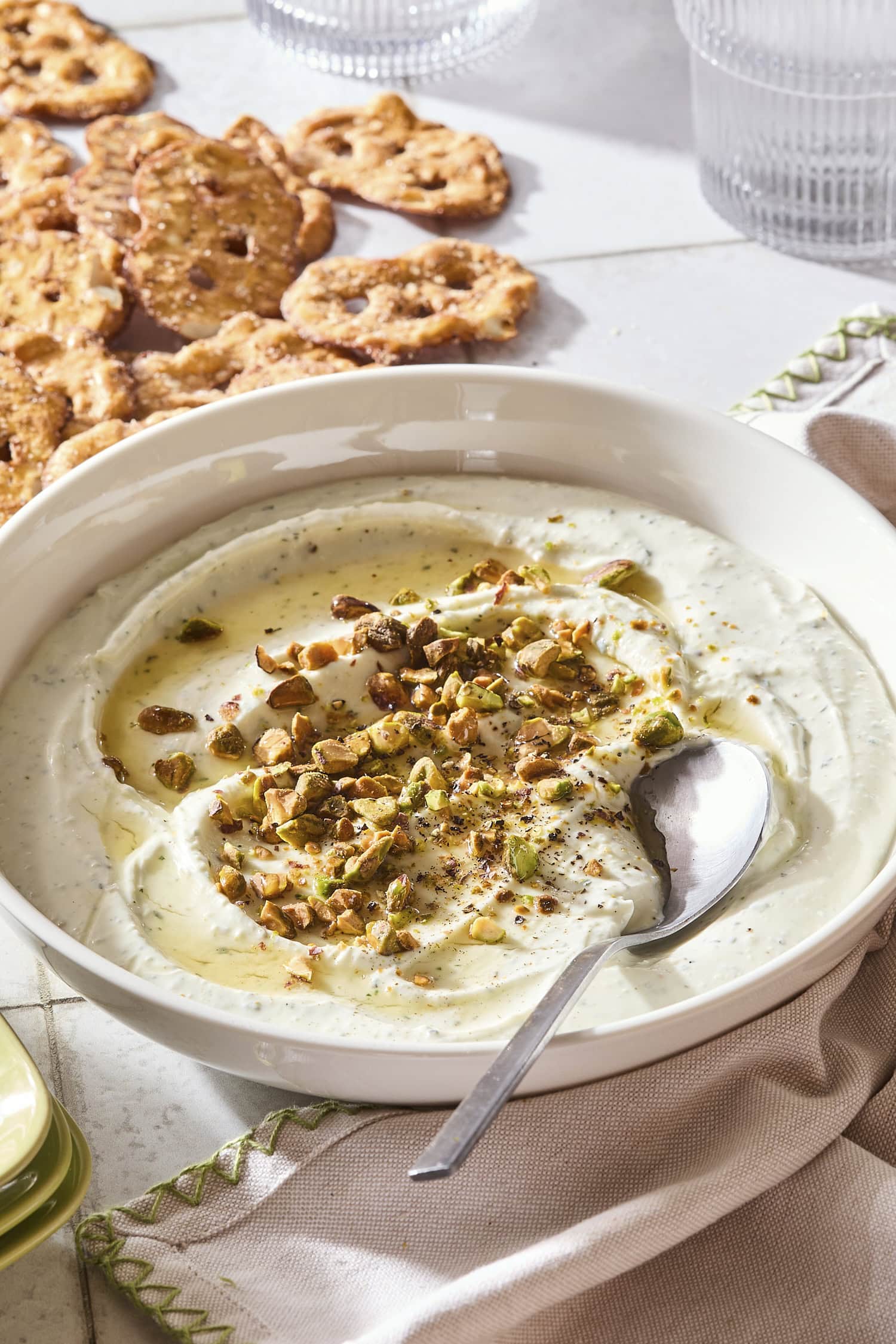 Whipped goat cheese dip topped with pistachios and hot honey with pretzels to the side.
