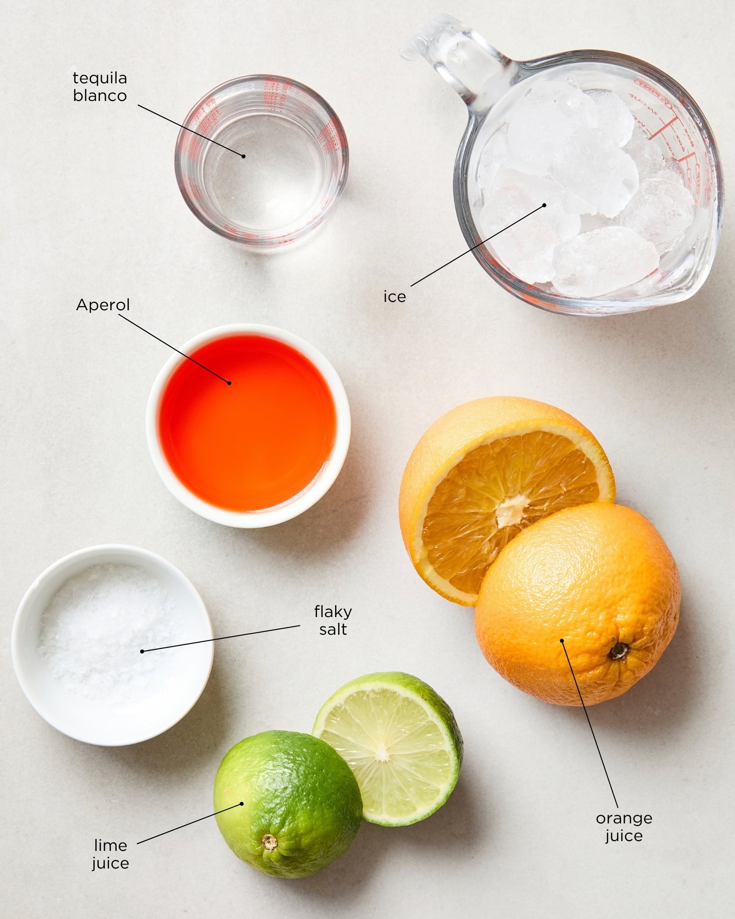 White surface filled with ingredients needed for an Aperol margarita.