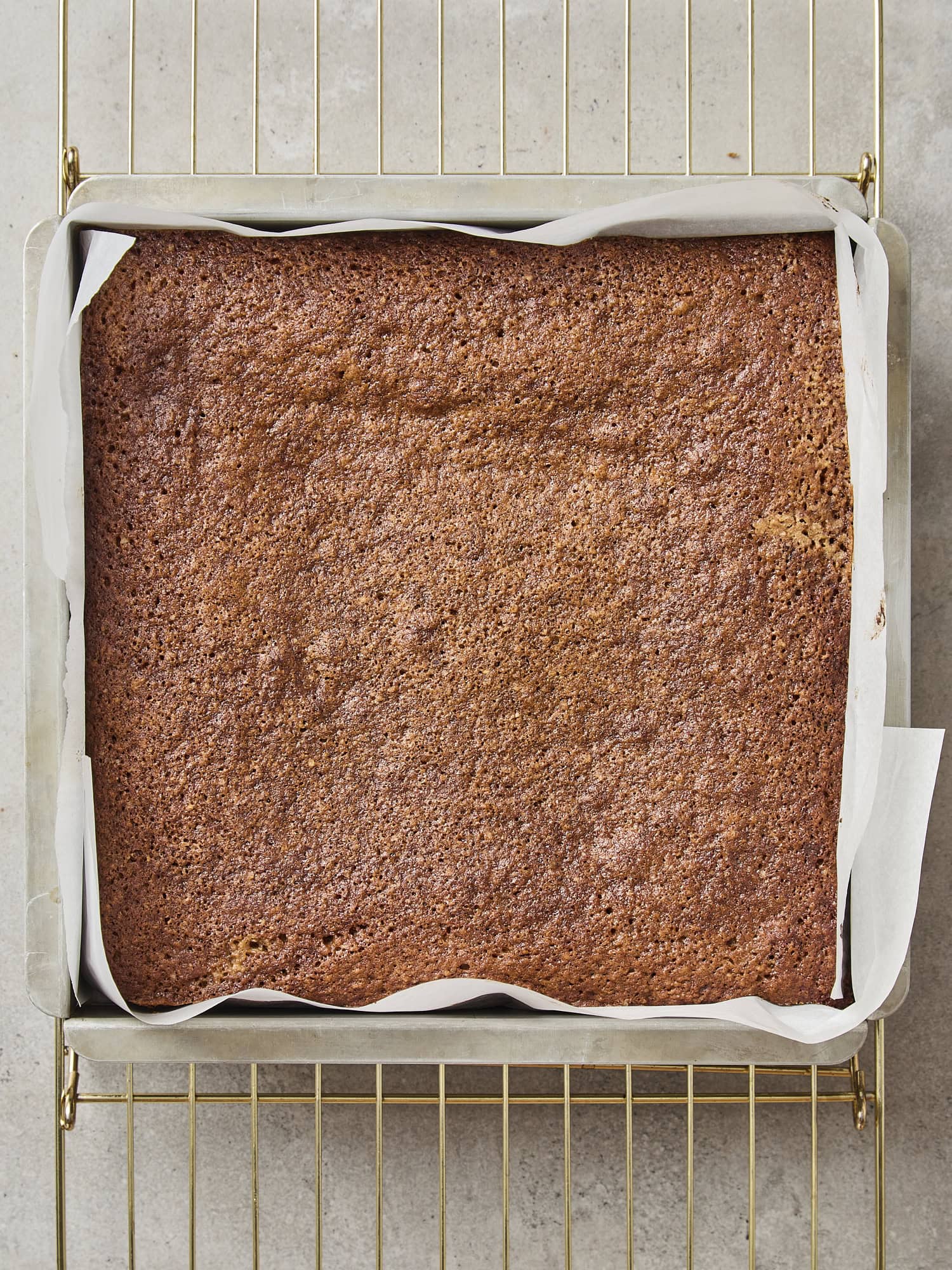 A square baking pan with freshly baked cake with brown crust on top.