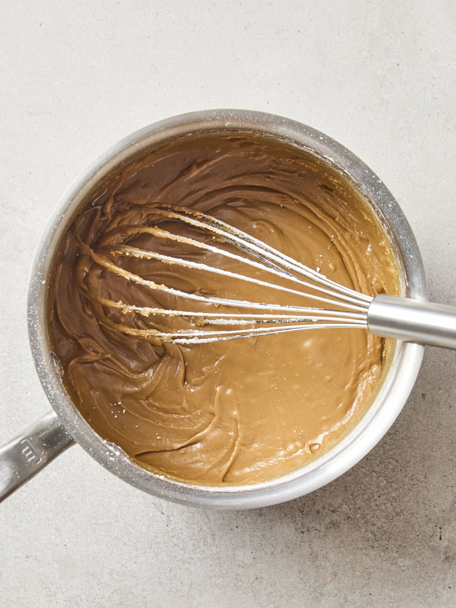 Saucepan with caramel frosting being whisked.