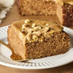 Applesauce cake with caramel frosting after being sliced from the rest of the cake.